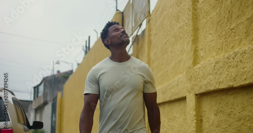 Картината върху платно Hispanic Afro-Latin man walking forward along yellow wall, confident and relaxed
