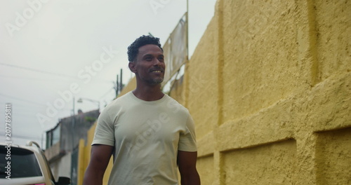 Foto Hispanic Afro-Latin man walking forward along yellow wall, confident and relaxed
