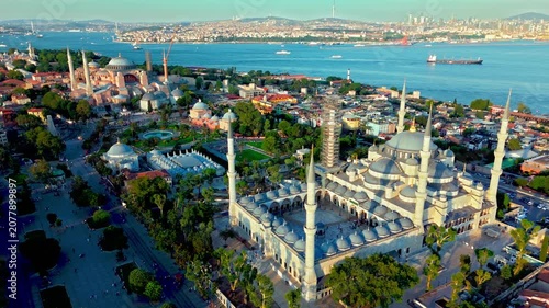 Drone view of the Blue Mosque and Sultanahmet district in Istanbul, Turkey. Sultanahmet Camii rises above historic rooftops, tree-lined streets and the blue sea.