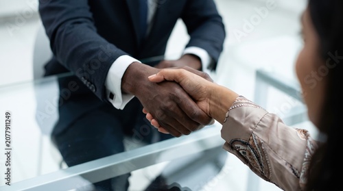 Close-Up of Diverse Professionals Handshake Over Glass Conference Table, Focused on Inclusive Hiring, Workplace Diversity, and Corporate Partnership Concept with Black and South Asian Individuals