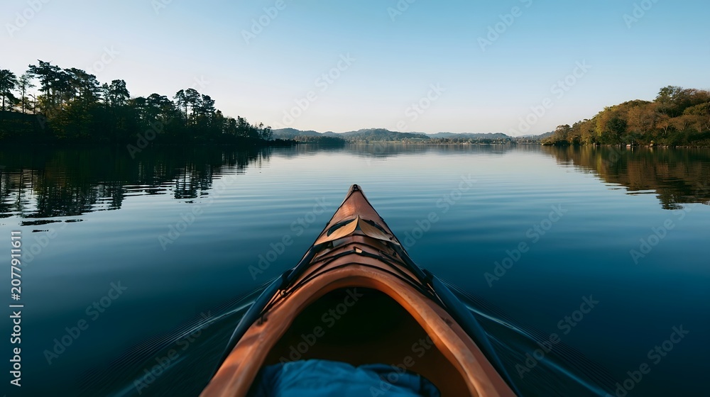Fototapeta premium A kayak glides across the calm surface of a serene lake reflecting natural beauty and tranquility