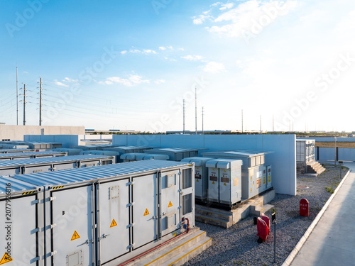 Outdoor energy storage station with battery container arrays under clear blue sky