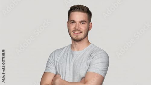Smiling young man with arms crossed posing confidently