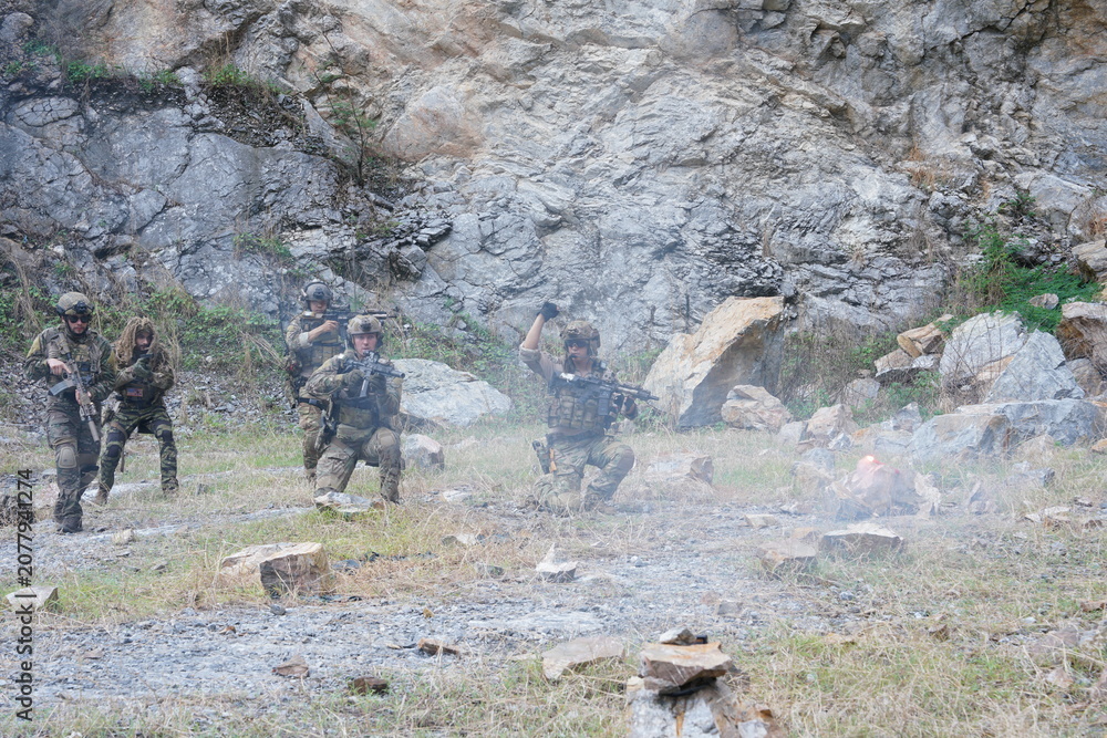 Fototapeta premium A group of soldiers in military uniforms carrying BB guns were randomly attacked and taken down during a military exercise while playing a game. 