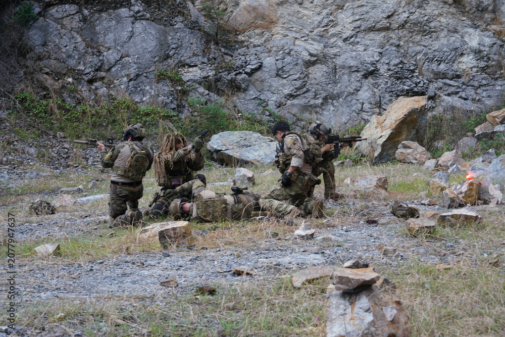 Fototapeta premium A group of soldiers in military uniforms carrying BB guns were randomly attacked and taken down during a military exercise while playing a game. 
