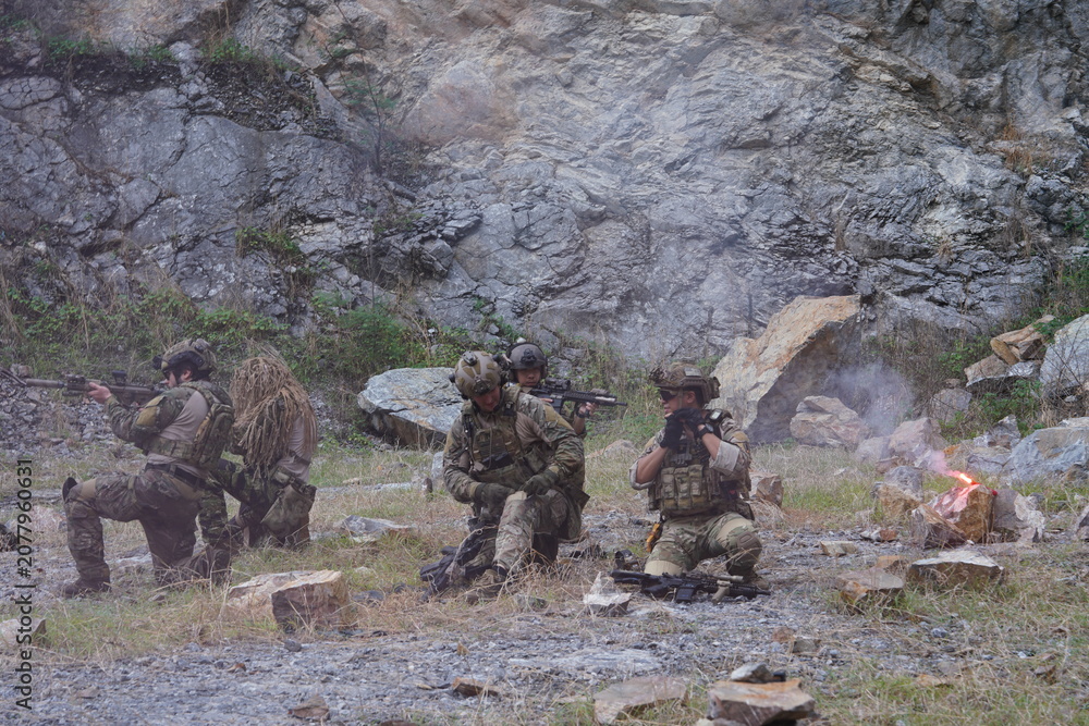 Fototapeta premium A group of soldiers in military uniforms carrying BB guns were randomly attacked and taken down during a military exercise while playing a game. 