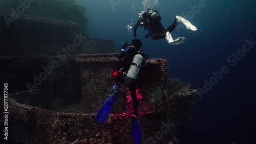 Scuba Divers Taking Photos from the Stern of a Sunken Shipwreck Underwater