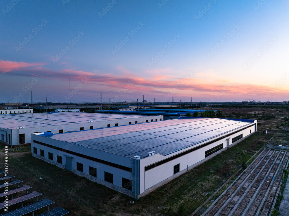 Fototapeta premium Industrial park rooftop photovoltaic energy storage station at dusk with sunset and clear sky