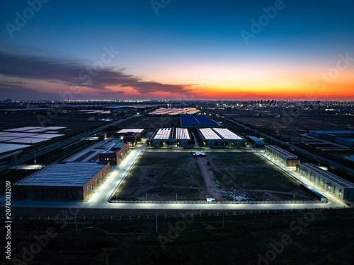 Aerial view of industrial park at dusk with illuminated buildings and solar panels