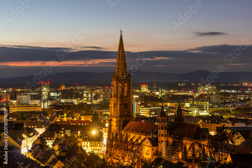 Evening view of Freiburg with illuminated cathedral and city lights