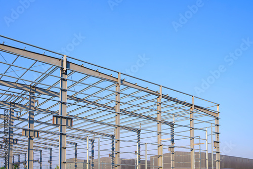 Factory warehouse industry building steel structure design, Metal framework of modern industrial buildings in construction site against blue sky background, perspective side view