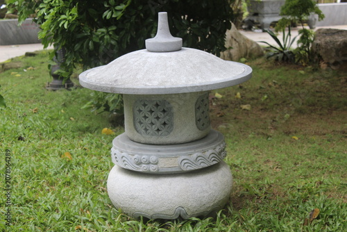 Stone lantern decorative sculpture standing on green grass in tranquil garden area.