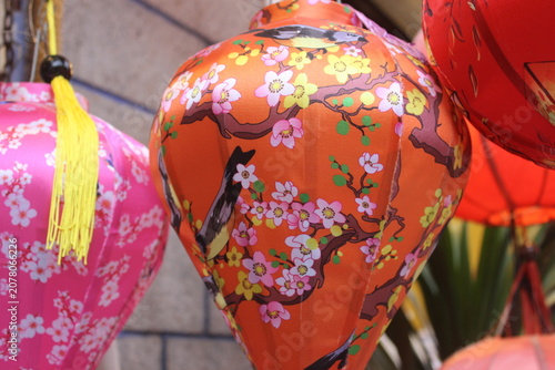 Vibrant orange lantern adorned with cherry blossom branches and colorful birds.