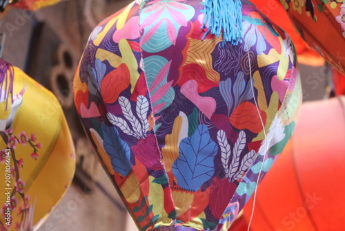 Multi colored lantern covered in abstract shapes and tropical leaf artistic motif.