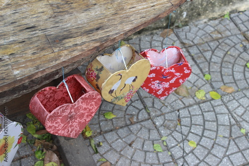 Heart shaped fabric lanterns hanging from a wooden table on a city street corner.