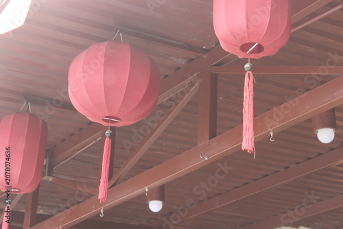 Red silk lanterns hanging from wooden ceiling in traditional vietnamese architecture.