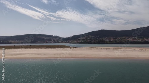 Aerial view showing a speed boat cruising by the sandbank and coastline of galicia