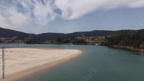 Aerial view showing a speed boat cruising by the sandbank and coastline of galicia
