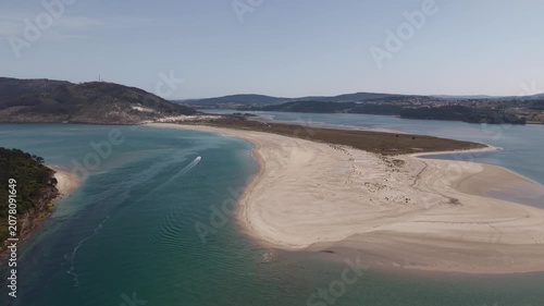 Aerial view showing a speed boat cruising by the sandbank and coastline of galicia