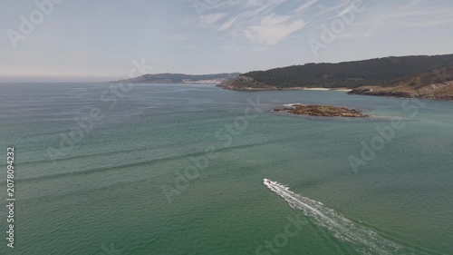 Aerial view showing a speed boat cruising by the sandbank and coastline of galicia
