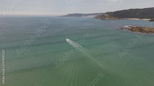Aerial view showing a speed boat cruising by the sandbank and coastline of galicia