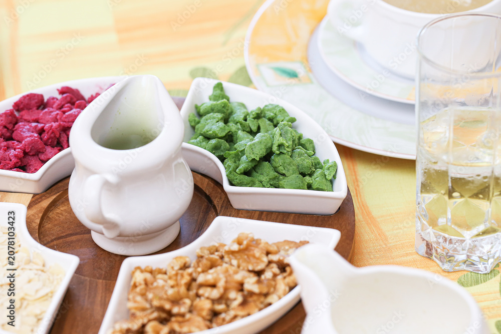 Fototapeta premium Colorful beetroot and spinach soup dumplings. Traditional soup garnish background for homemade cooking. Walnut and almond toppings enrich classic recipe. Rustic table serving looks fresh.