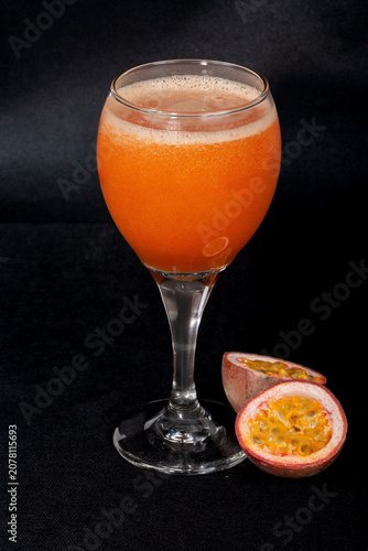 This refreshing tropical drink is a thick, bright orange cocktail made with passion fruit juice. Served in a classic stemmed glass, it may include fresh fruit pulp and seeds for a more flavorful twist