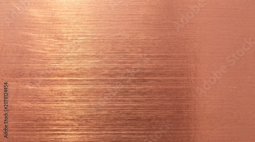 A close-up view of a brushed copper metal surface with a horizontal grain and subtle scratches