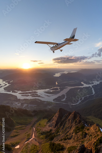 Fotografía Small Plane Flying Over Mountain Valley at Sunset With River Landscape and Drama