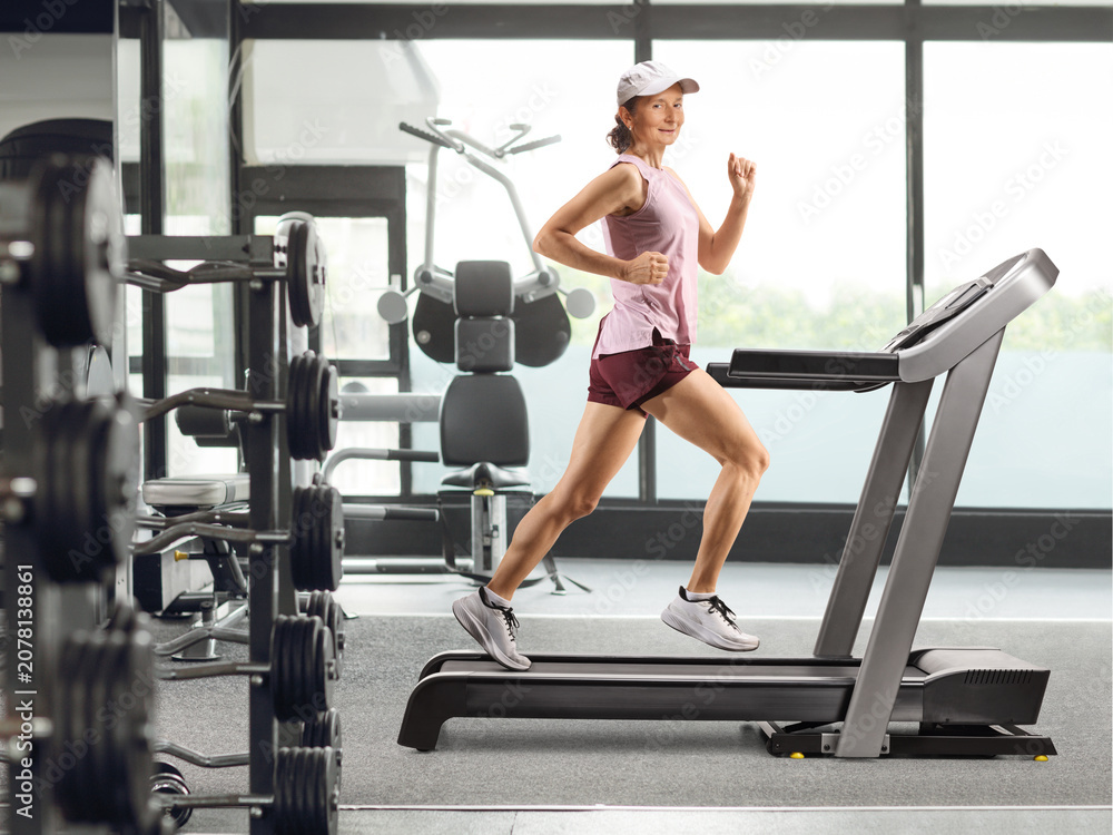 Fototapeta premium Woman running on a treadmill at a gym