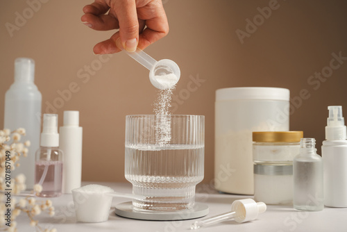 Woman adding collagen supplement to water alongside skincare products and self care routine