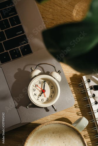 Time management concept with alarm clock, laptop and coffee on home office desk, top view workspace