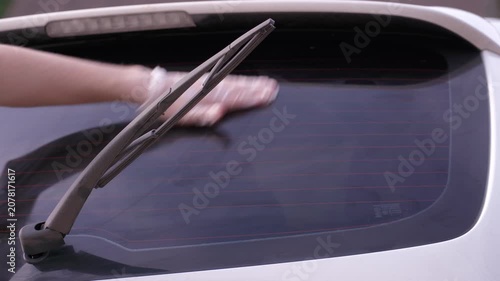 A man applies a ceramic anti-rain coating to the windows and headlights of a car.