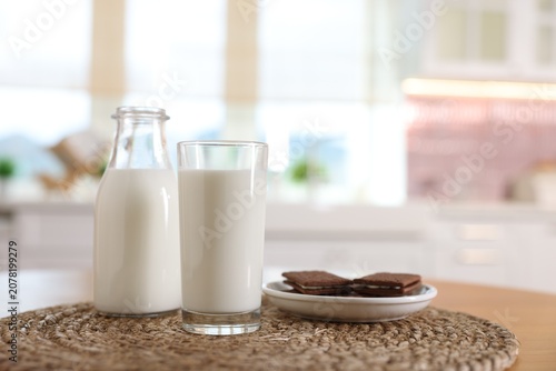 Obraz na plátně Fresh milk and chocolate sandwich cookies on wooden table in kitchen