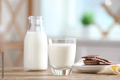 Foto Fresh milk and chocolate sandwich cookies on wooden table in kitchen