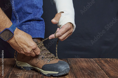Injured person with arm cast tying shoelaces