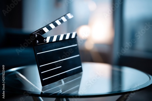 Movie clapperboard on glass table with film set background in soft light
