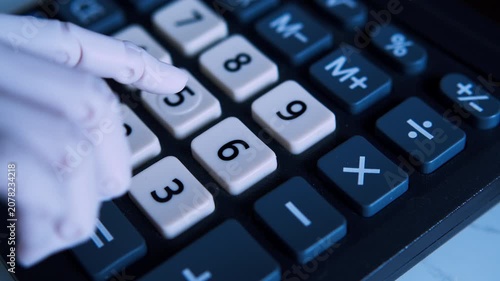 POV macro of an AI robotic hand pressing buttons on an office calculator. 