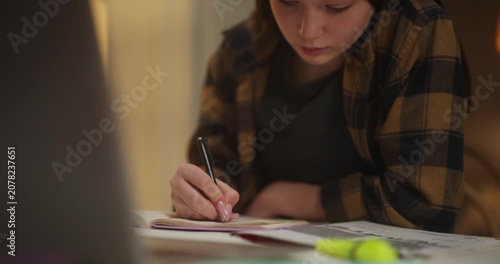 Young woman writing notes in a notebook at a desk