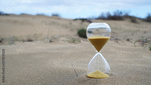 Hourglass with sand flowing on a dry desert landscape, symbolizing the urgent global crisis of climate change, desertification, and the limited time remaining for environmental action