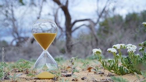 Hourglass standing on arid land representing climate change time running out