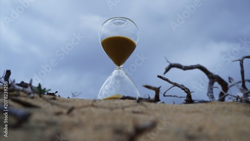 Hourglass with sand flowing, symbolizing time running out for climate change and the urgent need for action against desertification and ecological crisis in dry, arid land