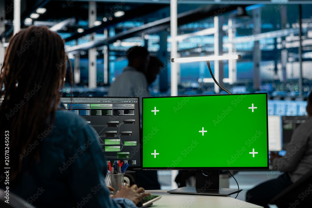 Obraz premium Data center engineer uses a green screen computer in a data center for server operations, screen replacement, and server workflow monitoring.