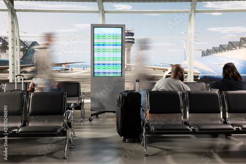 Obraz na plátne Carrying trolleys, silhouettes and people in hectic airport lobby generating blurred motion, moving fast, luggage and travelers passing metal chairs in air transportation hub, for air travel concepts