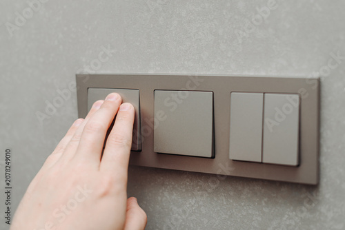 Obraz na plátně grey light switch attached to wall, minimalistic interior, man hand switching li
