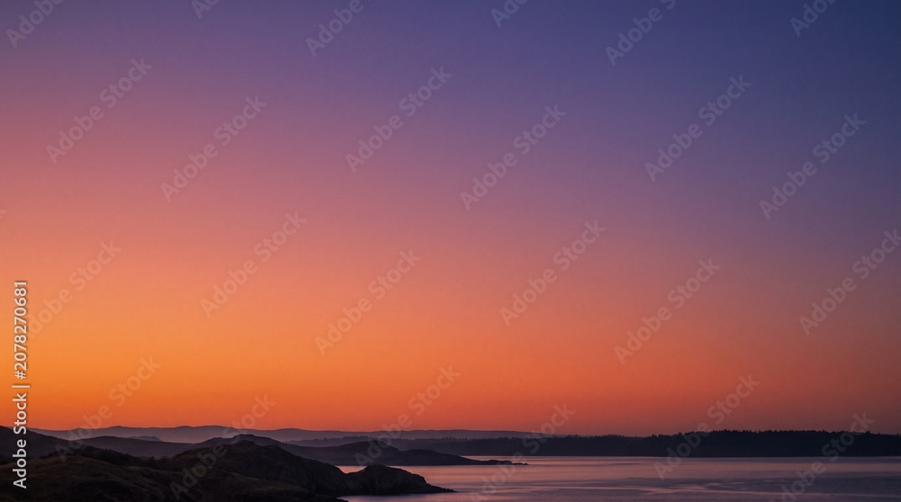 Fototapeta premium Vibrant sunset sky over calm water and distant hills with purple and orange hues