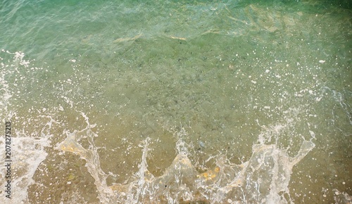Fotografie Turquoise sea surface with crushing waves and foam colorful water ariel shot sum