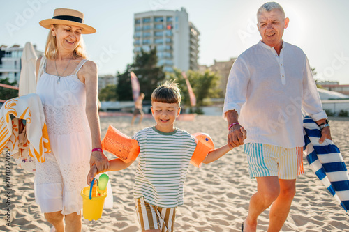Obraz na płótnie Grandparents Running Along Beach With Grandchildren On Summer Vacation