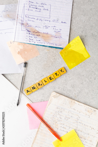 Concept of workplace stress,information overload, mental health, overwhelming workload, organization, and productivity challenges, Top view of handwritten notes, wooden letter spelling anxiety