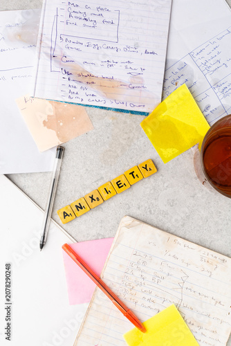 Concept of workplace stress,information overload, mental health, overwhelming workload, organization, and productivity challenges, Top view of handwritten notes, wooden letter spelling anxiety